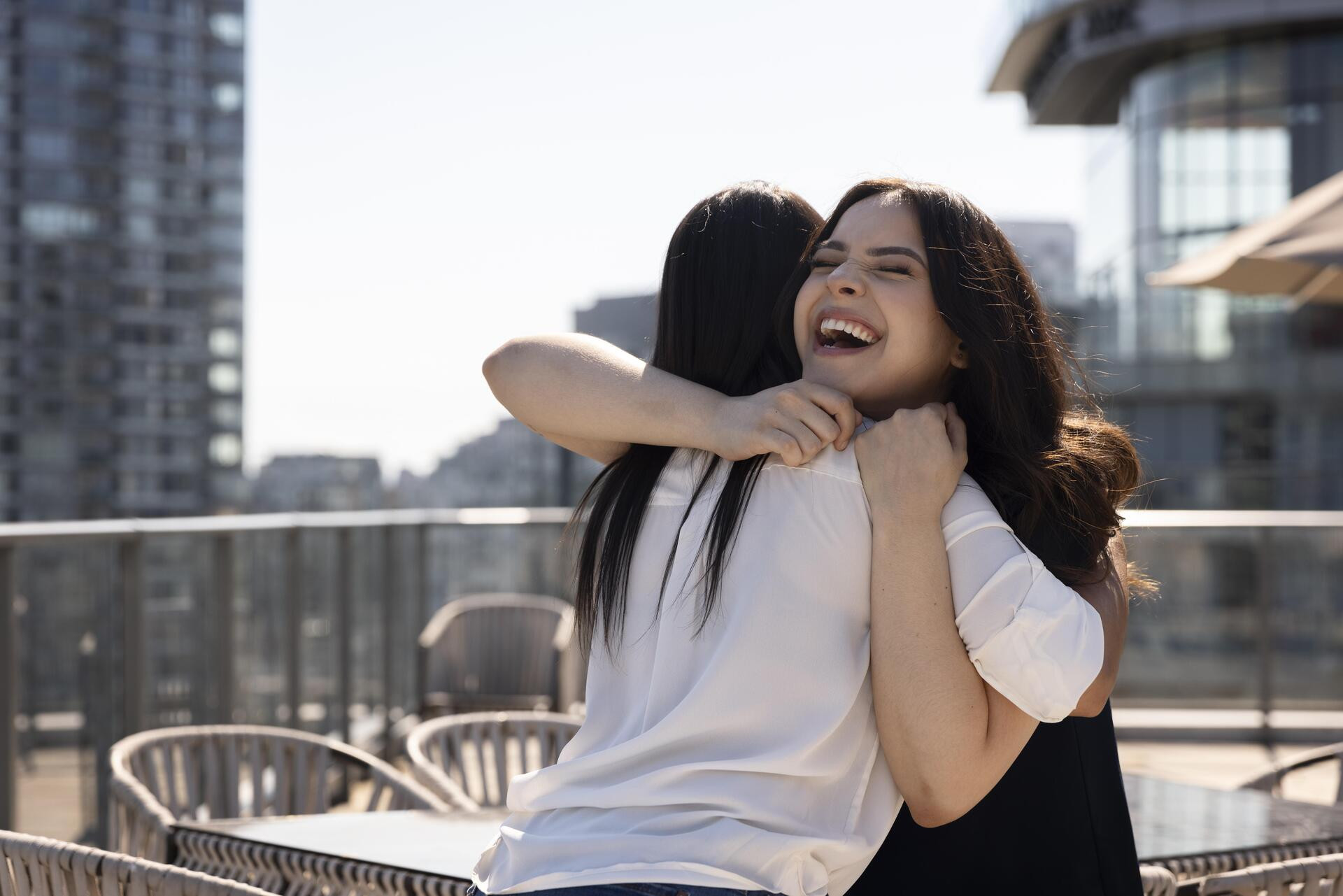 two female friends seeing each other rooftop terrace hugging (1).jpg