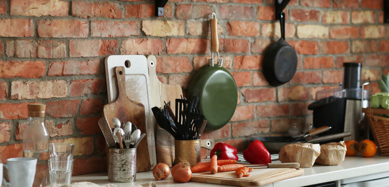 Kitchen utensils lined up against a brick wall.