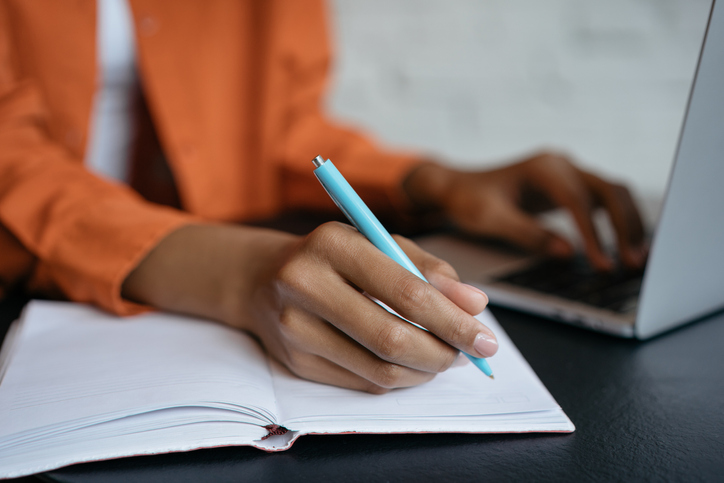 close-up_shot_of_student_hand_holding_pen_and_writing_in_notebook